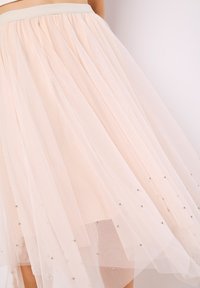 Helle rosa Tüllrock mit einem enganliegenden Bund. Mehrere Lagen mit silbernen Perlenakzenten. Weiche, leichte Textur.