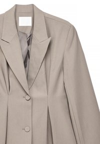 Blazer beige a medida con solapa con muesca, cierre de dos botones y hombros estructurados. Tejido liso con un brillo sutil.