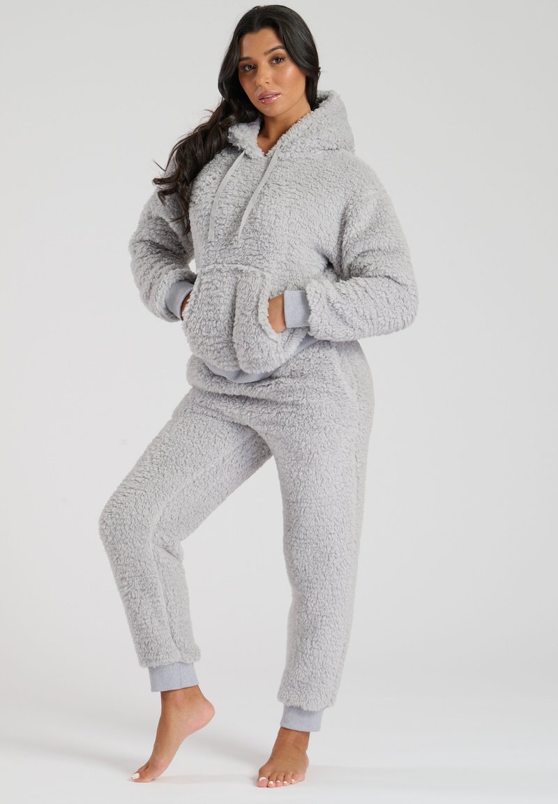 Conjunto de loungewear de felpa gris y esponjosa que incluye un pulóver con capucha y un bolsillo frontal, acompañado de pantalones ajustados a juego con puños acanalados.