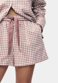 Shorts à motif vichy mauve et blanc, avec une taille élastique, un cordon de serrage et une fermeture à bouton à l'avant. Tissu doux avec poches.