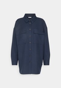 Mörk marinblå knappen-up skjorta gjord av tyg med en slät yta. Har en klassisk krage, två framfickor och lång ärm.