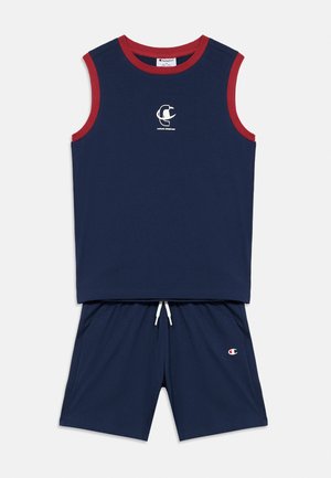 Marineblaues ärmelloses Sporttop mit roter Paspelierung und passenden Shorts mit weißem Kordelzug sowie kleinen Markenlogos auf Top und Shorts.