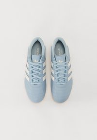 Jasnoniebieskie buty sportowe z białymi paskami, cholewką z teksturowanej skóry, sznurowaniem i elastyczną gumową podeszwą.