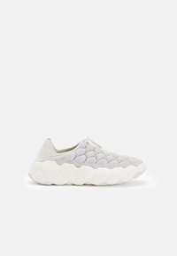 Szürke kötött slip-on cipők párnázott, texturált felsőrésszel, fehér gumitalppal és világoszöld részletekkel. Lekerekített forma, modern dizájn.