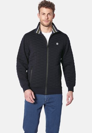 Men's navy quilted jacket with a zip front, striped collar, side pockets, and textured pattern. Fabric appears soft and lightweight.