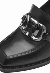 Černé kožené mokasíny s obdélníkovou špičkou a výrazným metalickým řetězcem přes nárt. Hladký povrch se šitými okraji.