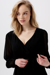 Schwarzes Wickelkleid mit langen transparenten Ärmeln, V-Ausschnitt und taillierter Passform. Es hat eine weiche Textur und eine Bindeschließe in der Taille.