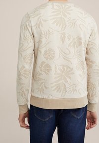 Beige texturovaná mikina s jemným květinovým vzorem, žebrované manžety a pas. Kombinováno s tmavě modrými džíny. Jednoduchý, ležérní design.