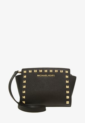 Czarna kopertówka na nadgarstek Michael Kors z złotymi piramidalnymi ćwiekami zdobiącymi przód oraz dopasowanym czarnym paskiem na nadgarstek.