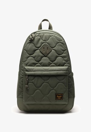 Quilted green backpack with a rounded shape, front zippered pocket, diamond accent, and textured fabric for added detail.