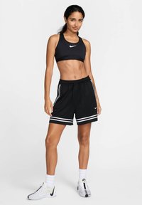Black sports bra and black shorts with white stripes. The shorts feature an elastic waistband and a drawstring, made of lightweight fabric.