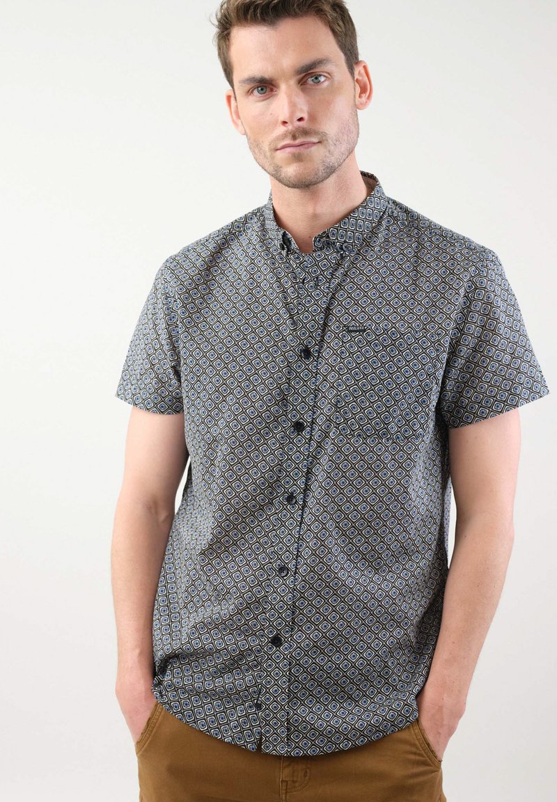 Korte mouw button-up shirt in donkere stof met een geometrisch patroon van blauwe en beige diamanten, met een borstzak en een gestructureerde kraag.