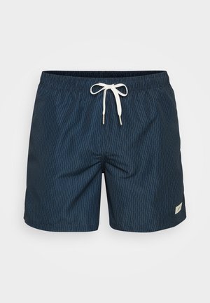 Shorts de bain bleu marine avec un motif en chevrons, taille élastique avec cordon de serrage et une petite étiquette de marque sur le côté inférieur.