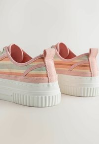 Baskets basses avec des rayures pastel rose, orange et beige, semelles épaisses blanches texturées et languettes en tissu au talon.