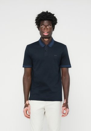 Navy polo shirt made of breathable cotton, featuring a contrasting blue striped collar and cuffs, with a subtle logo on the chest.