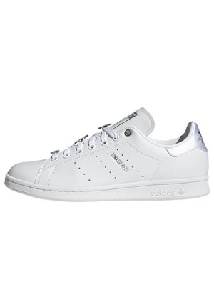 White leather sneakers with circular perforations, silver accents, and white rubber sole. Features flat laces and a classic low-top design.