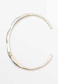 Bracciale rigido in metallo color oro con design ondulato, caratterizzato da una superficie testurizzata e estremità lucide. Nessun meccanismo di chiusura visibile.