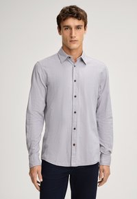 Camicia grigia chiara con maniche lunghe, bottoni frontali e tessuto texture, colletto a punta e bottoni marroni.
