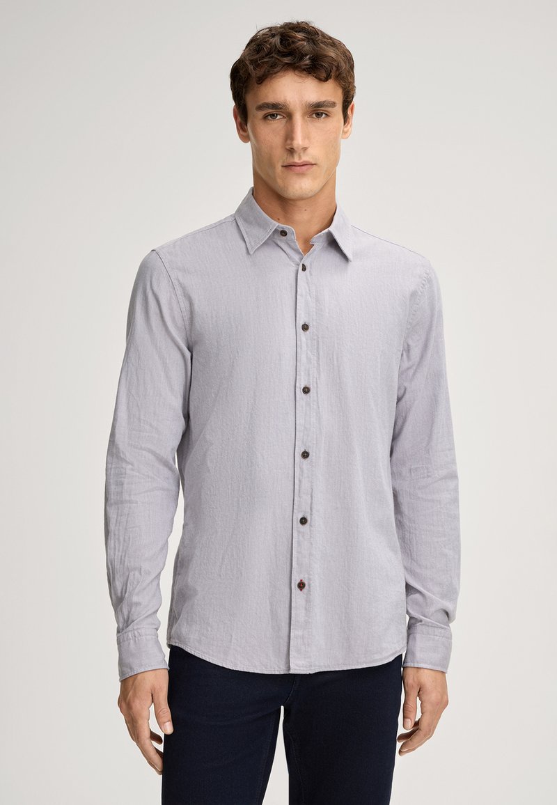 Camicia grigia chiara con maniche lunghe, bottoni frontali e tessuto texture, colletto a punta e bottoni marroni.
