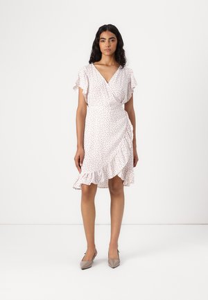 Rochie albă cu flori, cu mâneci și tiv volanate, având talie ajustată și fustă evazată. Purtată cu pantofi cu vârf ascuțit de culoare gri deschis.