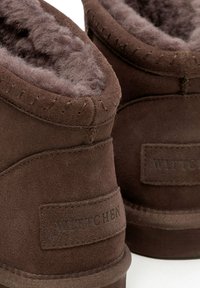 Stivaletti alla caviglia in pelle scamosciata marrone con morbida fodera grigia, cuciture a vista e logo "Wittchen" in rilievo sul tallone.