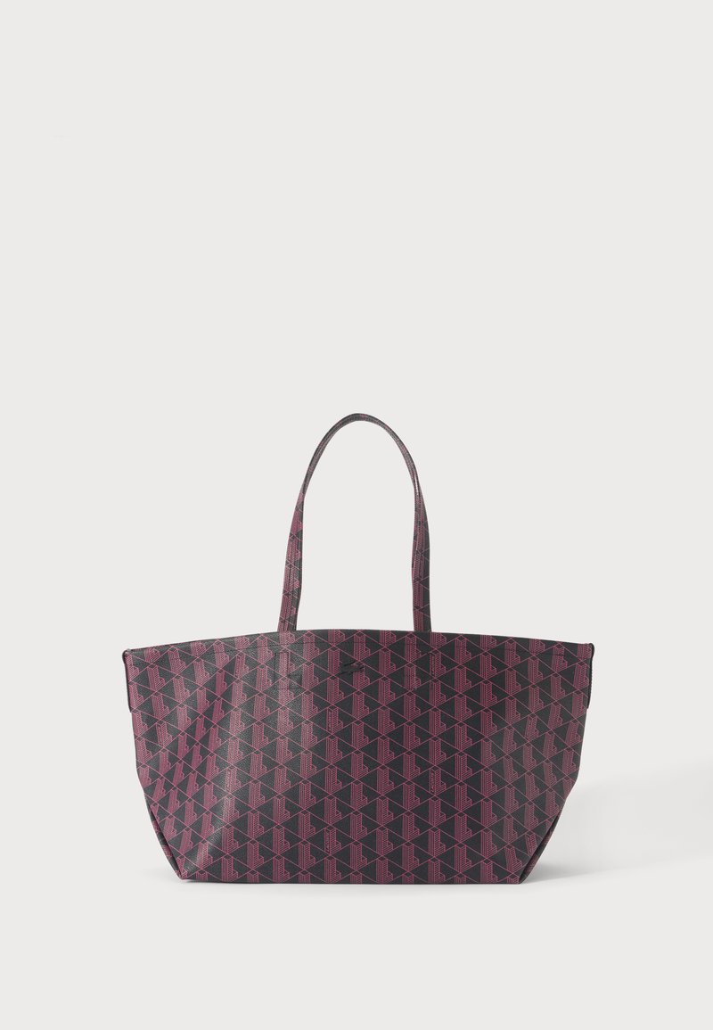 Grand sac cabas avec fond sombre et motif géométrique rose, deux bretelles et une large ouverture sur le dessus.