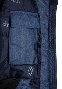 Interno di giacca blu scuro con una tasca texture dotata di pattina e un rivestimento decorato con forme geometriche astratte.