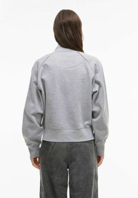 Grauer Sweatshirt mit Rundhalsausschnitt und Raglanärmeln. Verfügt über eine lockere Passform und einen gerippten Saum, hergestellt aus weichem Baumwollmischgewebe.