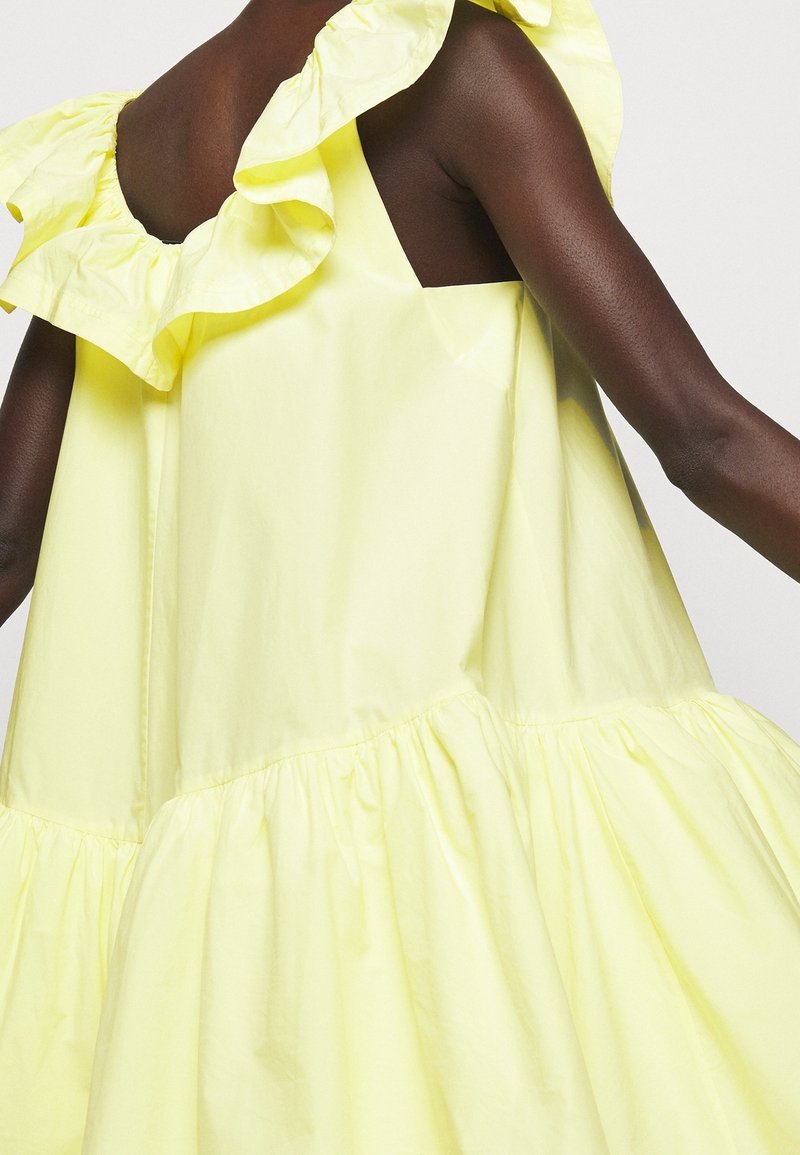 Robe en coton jaune avec épaules à volants, coupe décontractée et ourlet inférieur froncé pour une silhouette volumineuse.