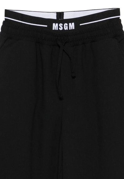 Pantalons de survêtement noirs en tissu texturé, avec une taille élastique et un cordon blanc, portant le logo MSGM contrastant à l'avant.