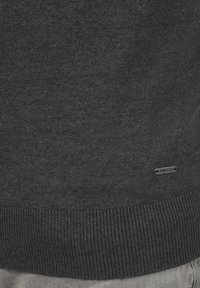 Suéter gris oscuro con una textura suave, dobladillo acanalado y una pequeña etiqueta "JEANSCODE" en el lado inferior. Diseño simple, sin patrones ni acentos.