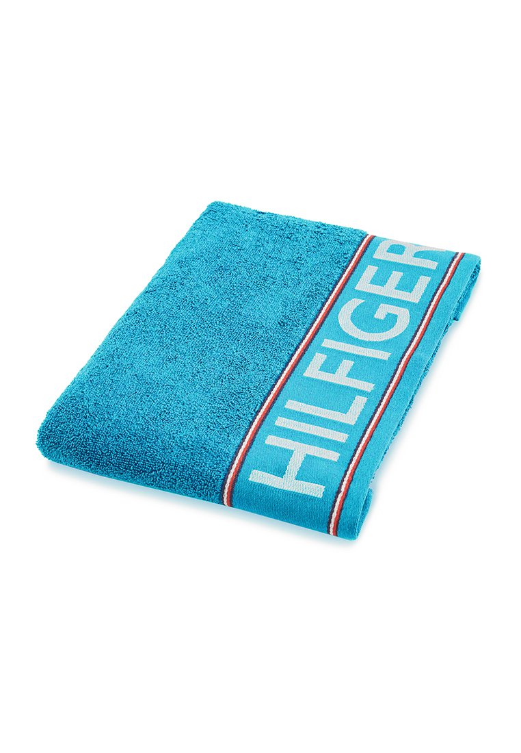 Türkises Handtuch mit strukturierter Oberfläche, ausgestattet mit einem weißen "HILFIGER"-Logo und roten Akzentstreifen entlang der Kante.
