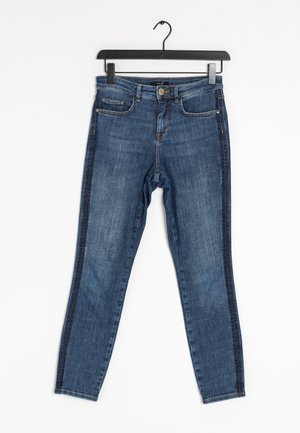 Tummansiniset denim-skinnyfarkut, joissa on viisi taskua, edestä napillinen suljenta ja kontrastiväriset reunukset sivuilla. Sileä tekstuuri ja istuva malli.