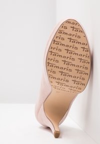 Chaussure à talon haut en daim rose avec un bout pointu et un talon fin. La semelle présente une marque imprimée et une étiquette de taille "37".