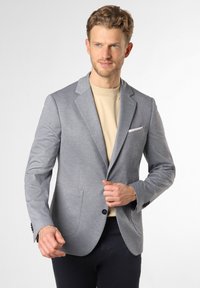Grau strukturierter Blazer mit Revers, zwei vorderen Taschen, einreihiger Knopfverschluss und einem kontrastierenden beigen Hemd darunter.