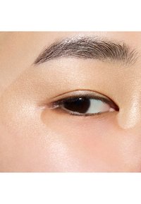 Close-up van een mensenoog met een gladde beige ooglid, een donkerbruine iris, subtiel gedefinieerde wimpers en een goed verzorgd donker wenkbrauw.