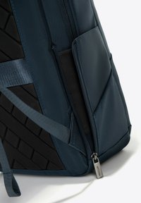 Marineblauwe rugzak gemaakt van duurzaam materiaal, met een gestructureerde zwarte zijpaneel, ritssluitingen en verstelbare schouderbanden.