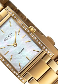 Montre en quartz dorée avec un boîtier rectangulaire, un cadran en nacre, des index horaires dorés et une lunette ornée de cristaux. Bracelet en métal à maillons.