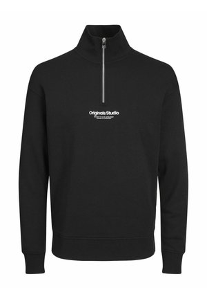 Melns džemperis ar augstu apkakli un ceturtdaļas rāvējslēdzēju. Uz krūtīm ir balts "Originals Studio" logo. Izgatavots no teksturēta auduma.