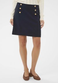 Tumši zila svārku izgatavota no gludas auduma, ar taisnu piegriezumu, piecām zelta pogām kreisajā pusē un sānu kabatām.