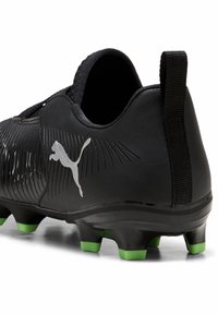 Crni nogometni kopač s teksturiranim gornjim dijelom, sa srebrnim Puma logotipom i kopačkama s zelenim vrhom na crnoj potplati za bolje prianjanje.