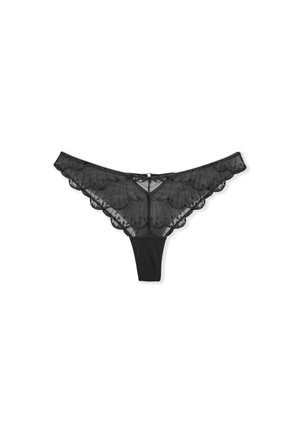 Tanga de encaje negro con bordes festoneados, que presenta un diseño frontal transparente y una parte trasera sólida. Detalles delicados con un pequeño cierre central.