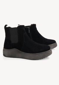 Bottes de cheville en suede noir avec une semelle en caoutchouc texturé, fermeture éclair sur le côté et panneaux élastiques pour un enfilage facile. Design simple et moderne.