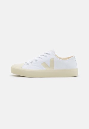 Sneaker bianche in canvas con suola in gomma beige, con un grande logo beige sul lato e design classico con lacci. Texture liscia.