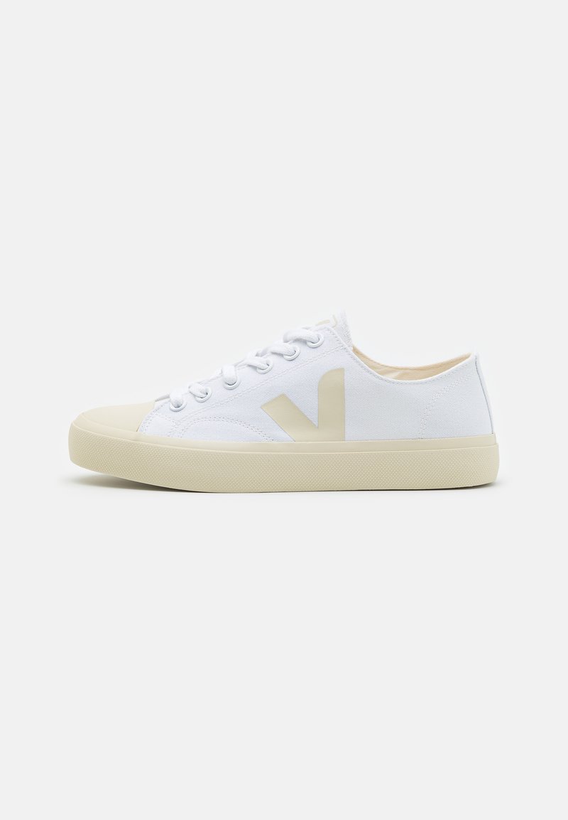 Hvite kanvas sneakers med en beige gummisåle, med en stor beige logo på siden og klassisk snøring. Glatt tekstur.