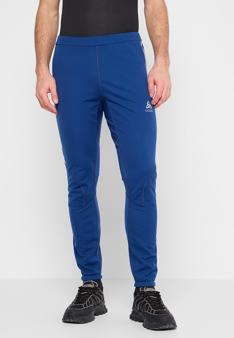 Niebieskie spodnie sportowe z elastycznego materiału, charakteryzujące się dopasowanym krojem, kontrastowymi szwami oraz logo na lewej udzie.