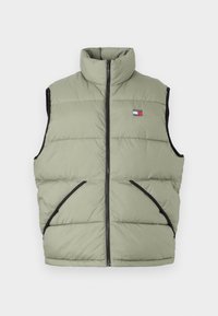 Olive green puffer vest with a high collar, front zipper, two side pockets, and black trim. Features a logo patch on the chest.