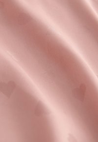 Soft pink fabric with subtle heart patterns, smooth texture, and a delicate sheen, draping gently in folds.