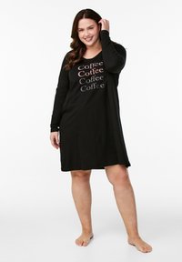 Vestito da notte nero, lungo fino al ginocchio, realizzato in un tessuto morbido, con scollatura rotonda e maniche lunghe, decorato con la scritta "Coffee" stampata in diversi colori sul davanti.