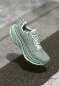 Chaussure de course vert menthe avec un dessus en maille, un col rembourré et une semelle texturée. Présente un renfort à l'avant-pied et des accents de logo sur les côtés.
